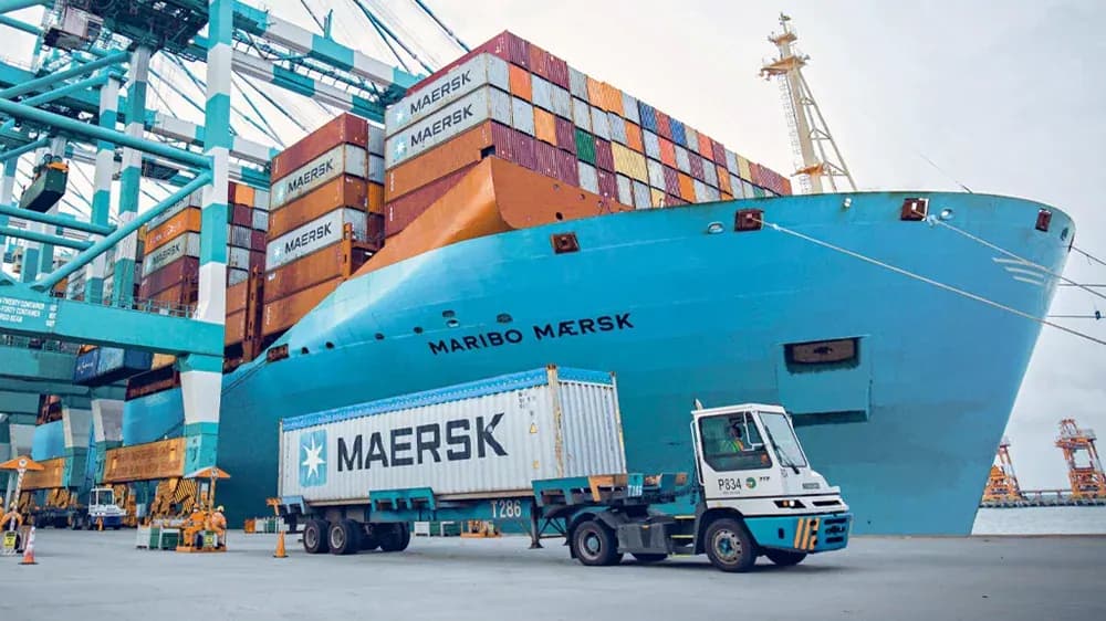 Maersk container ship at port with a Maersk container being moved by a terminal truck